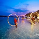 Performers dancing with rings of fire in the ocean
